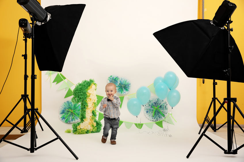 Cute baby boy on birthday decor background  at photo shooting